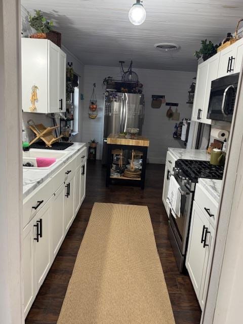 kitchen with dark hardwood / wood-style flooring, white cabinetry, and stainless steel appliances