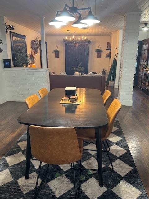 dining space featuring dark hardwood / wood-style flooring, decorative columns, a notable chandelier, and wood ceiling