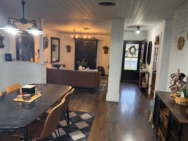 dining area with a chandelier, wood ceiling, dark wood-type flooring, and brick wall