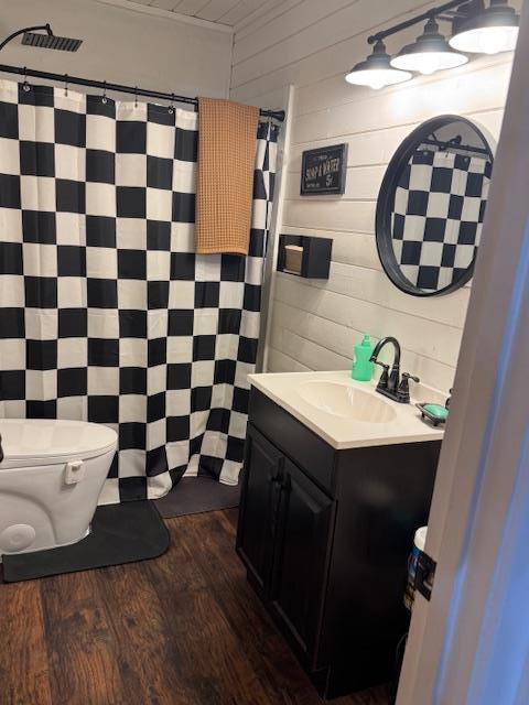 bathroom with hardwood / wood-style floors, vanity, toilet, and wood walls