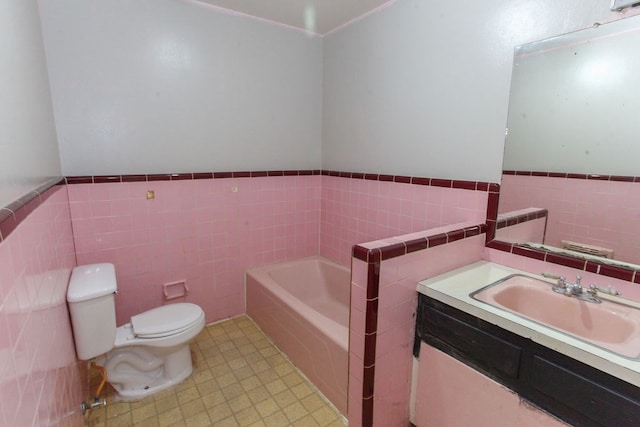 1309 Lexington Ave, Big Spring, TX 79720 - bathroom with tile walls, a garden tub, vanity, wainscoting, and tile patterned floors