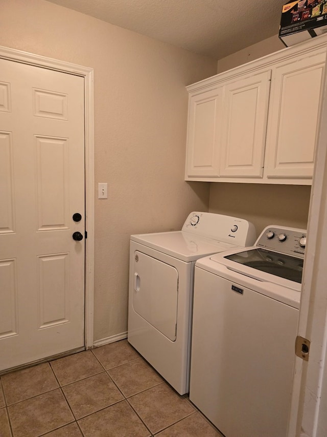 clothes washing area with cabinets, independent washer and dryer, a textured ceiling, and light tile patterned floors