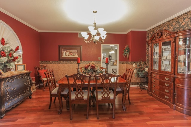 dining area featuring hardwood / wood-style floors, ornamental molding, and an inviting chandelier