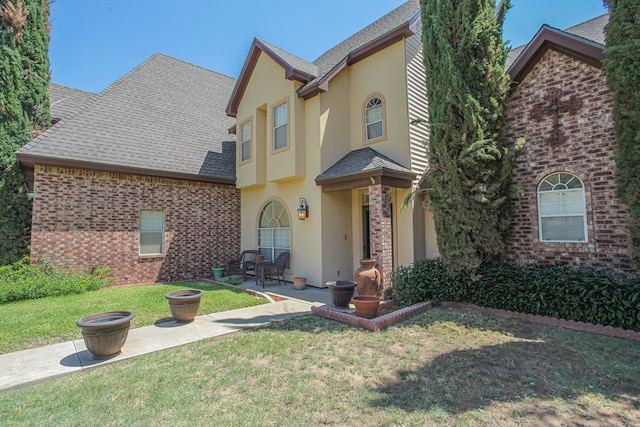 view of front of property featuring a front lawn and a patio