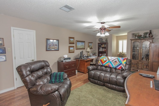 living room with hardwood / wood-style floors, a textured ceiling, and ceiling fan