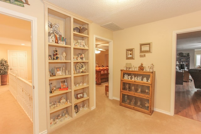 corridor featuring light carpet and a textured ceiling