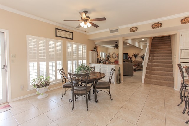 tiled dining area featuring ceiling fan and ornamental molding