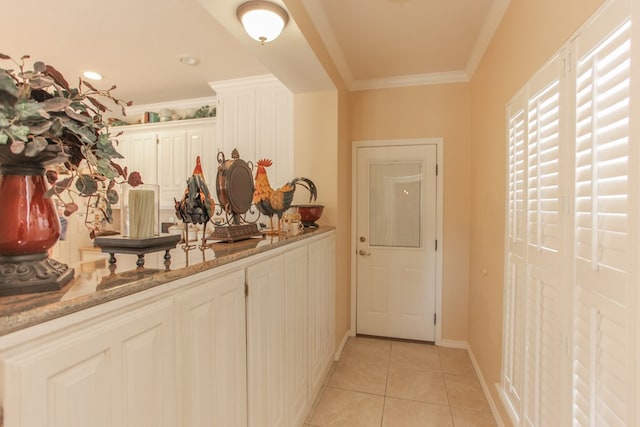 interior space with white cabinets, light stone countertops, crown molding, and light tile patterned floors