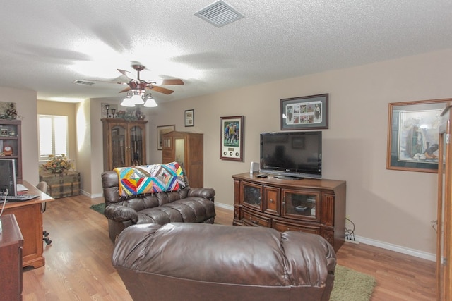 living room with a textured ceiling, light hardwood / wood-style flooring, and ceiling fan