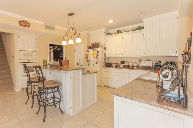 kitchen with light stone countertops, an inviting chandelier, crown molding, white appliances, and a kitchen island