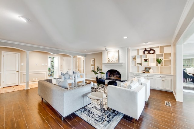 living room featuring decorative columns, a fireplace, dark wood-type flooring, and ornamental molding