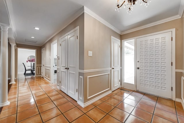 foyer entrance with decorative columns, crown molding, and light tile patterned flooring