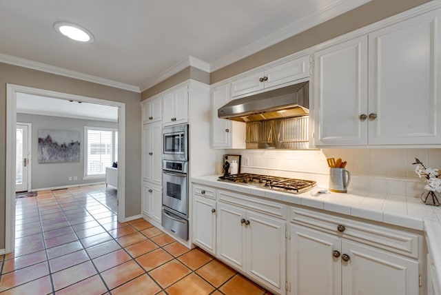 kitchen with white cabinetry, backsplash, tile countertops, light tile patterned floors, and appliances with stainless steel finishes