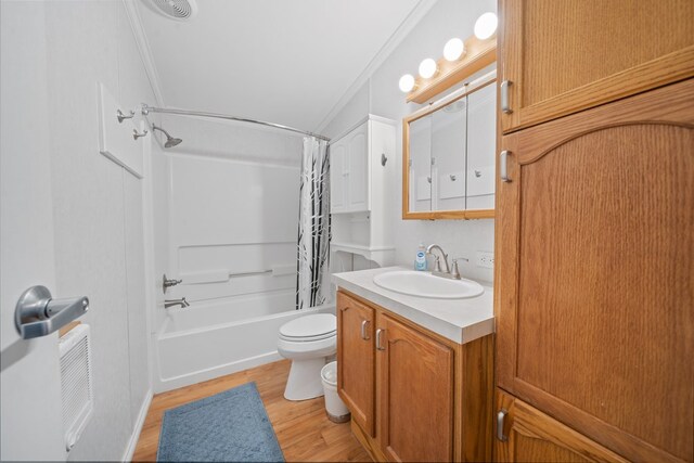 full bathroom featuring shower / bath combo with shower curtain, wood-type flooring, vanity, and ornamental molding