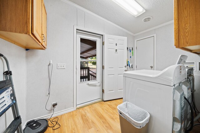 washroom featuring cabinets, light hardwood / wood-style flooring, a textured ceiling, washer / dryer, and ornamental molding