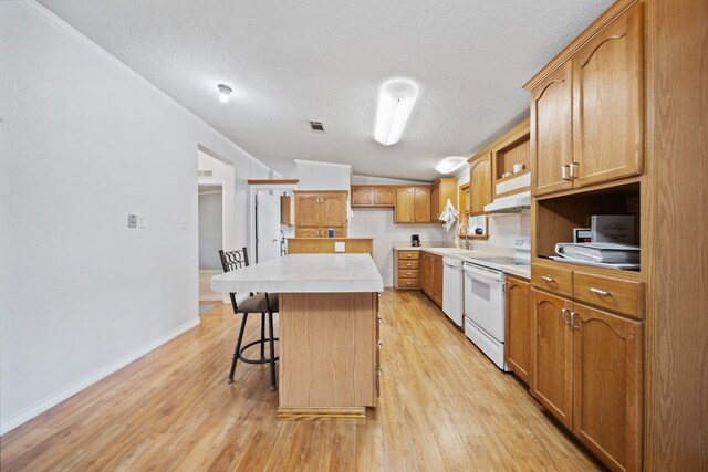 kitchen featuring a center island, a kitchen breakfast bar, vaulted ceiling, white appliances, and light wood-type flooring