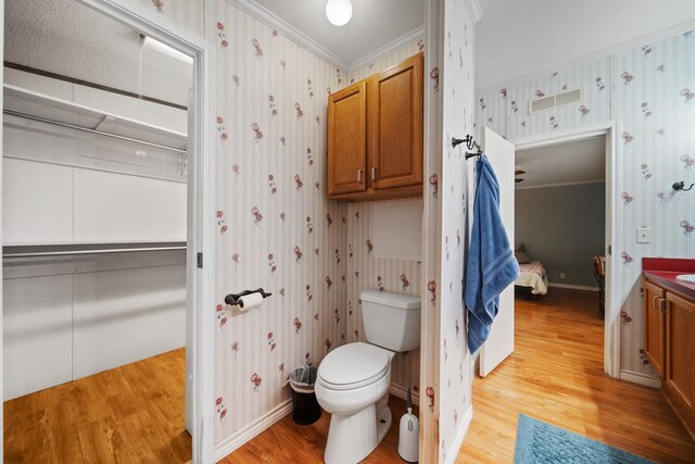 bathroom with toilet, hardwood / wood-style floors, vanity, and ornamental molding