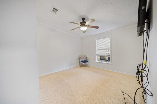 empty room with crown molding, ceiling fan, light colored carpet, and a textured ceiling