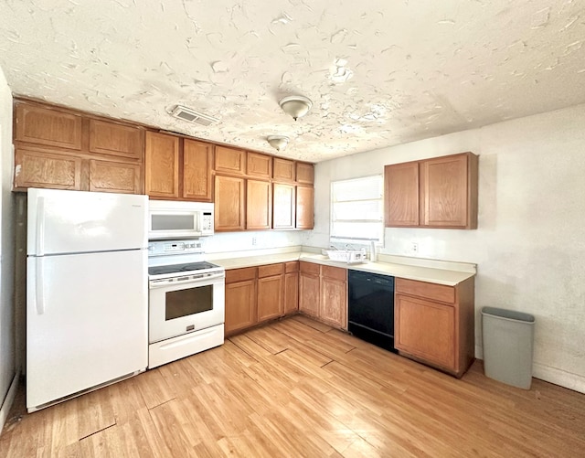 kitchen featuring light wood-type flooring, a textured ceiling, and white appliances