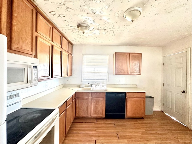 kitchen with sink, white appliances, light hardwood / wood-style flooring, and a textured ceiling