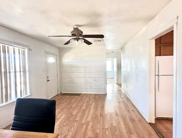 interior space with ceiling fan, a wealth of natural light, a textured ceiling, and light hardwood / wood-style floors