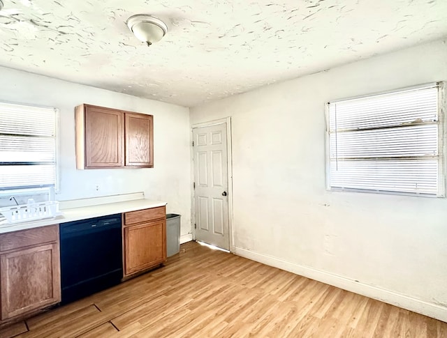 kitchen with a healthy amount of sunlight, dishwasher, light hardwood / wood-style floors, and a textured ceiling