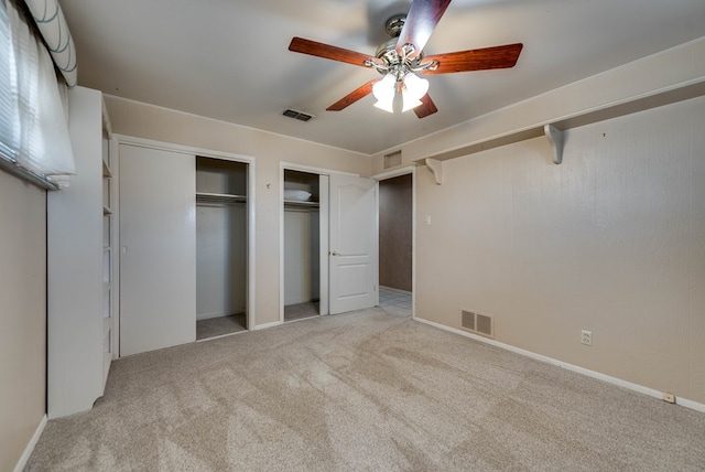 unfurnished bedroom with visible vents, carpet floors, and two closets