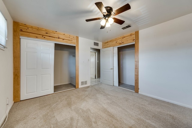 unfurnished bedroom featuring carpet floors, multiple closets, visible vents, and baseboards