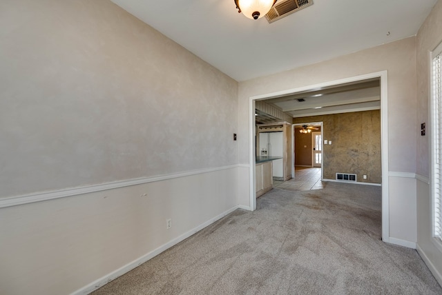 corridor featuring visible vents, baseboards, and light carpet