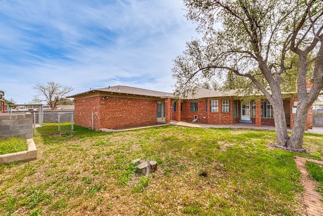 rear view of property featuring fence, a patio, a yard, and brick siding