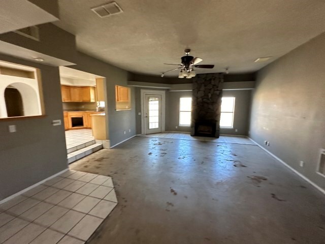 unfurnished living room featuring a wealth of natural light, a fireplace, and ceiling fan