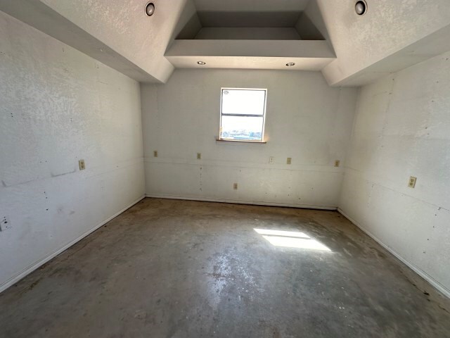 empty room featuring vaulted ceiling, a textured ceiling, and concrete floors