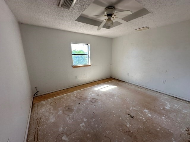 unfurnished room with ceiling fan and a textured ceiling