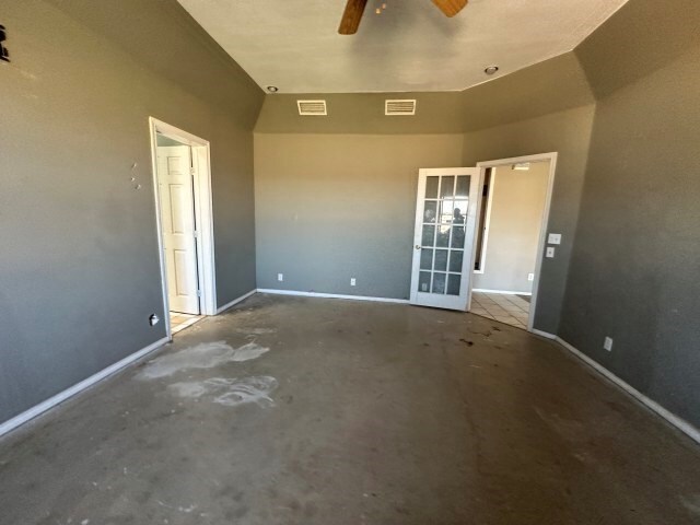 empty room with ceiling fan, french doors, and concrete floors