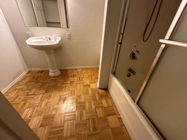 bathroom featuring shower / bath combination with glass door, sink, and parquet flooring