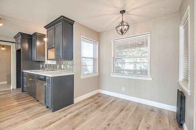 kitchen featuring backsplash, an inviting chandelier, hanging light fixtures, light hardwood / wood-style flooring, and stainless steel dishwasher