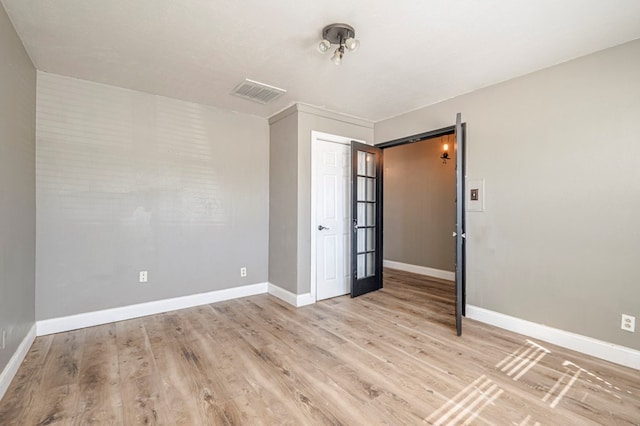 empty room featuring french doors and light hardwood / wood-style floors