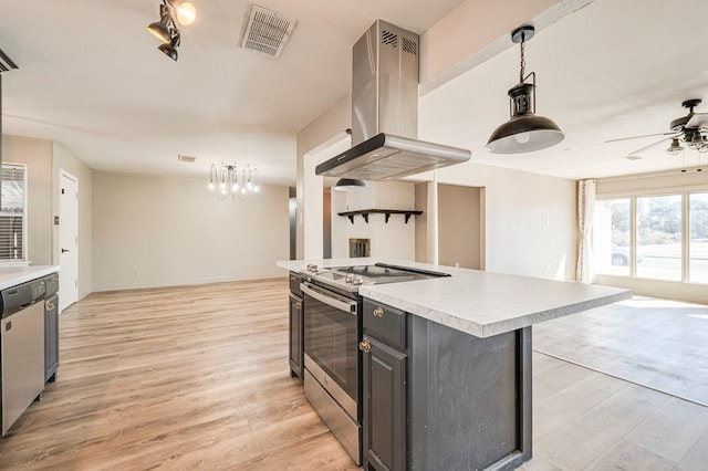 kitchen with light wood-type flooring, stainless steel appliances, decorative light fixtures, a kitchen island, and range hood