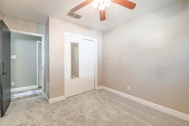 unfurnished bedroom featuring ceiling fan, a closet, and light colored carpet