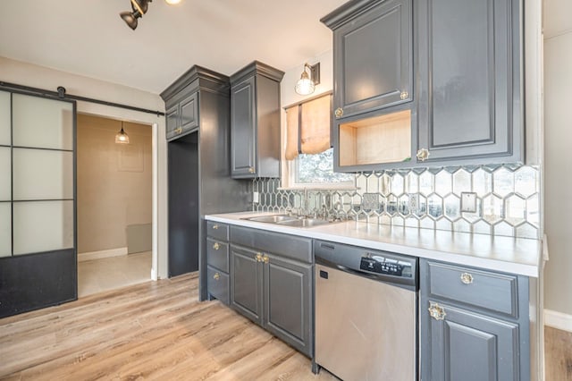 kitchen with dishwasher, sink, light hardwood / wood-style flooring, decorative backsplash, and a barn door