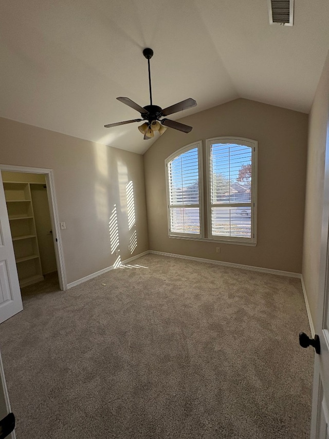 empty room with carpet floors, vaulted ceiling, and ceiling fan