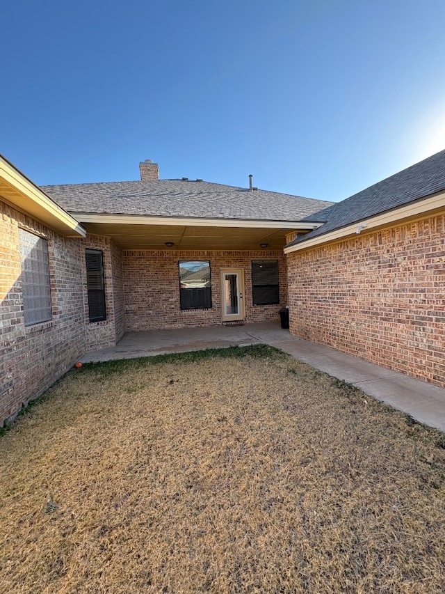 back of property with a lawn and a patio