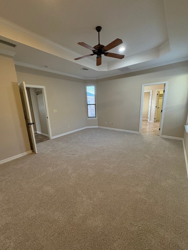 carpeted spare room with ceiling fan, ornamental molding, and a raised ceiling