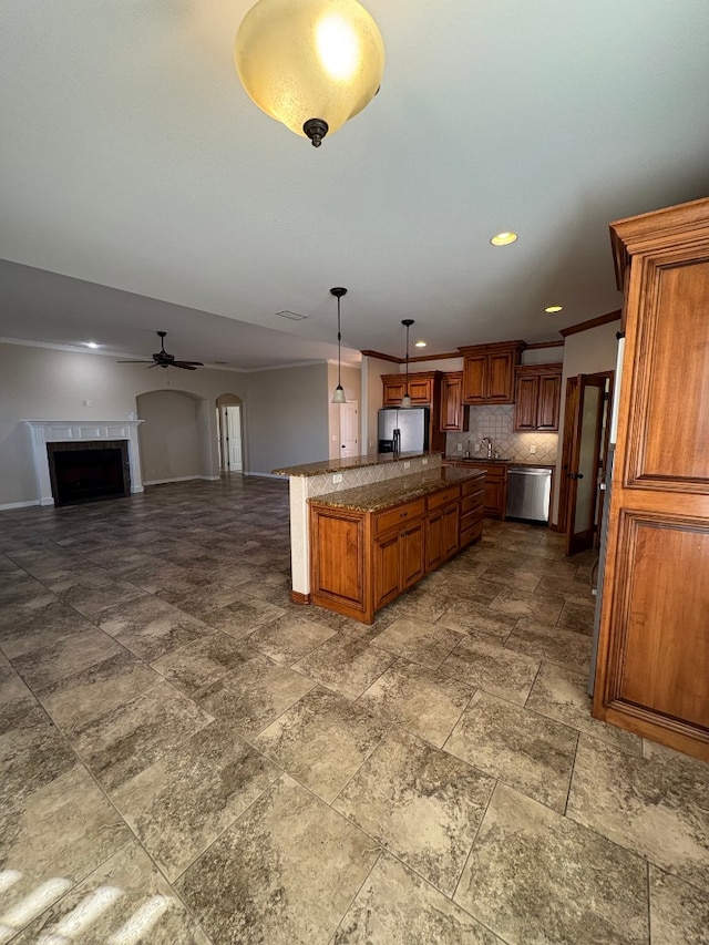 kitchen featuring ceiling fan, stainless steel appliances, tasteful backsplash, decorative light fixtures, and a fireplace