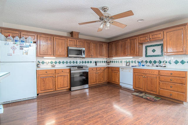 kitchen with a textured ceiling, decorative backsplash, stainless steel appliances, and dark hardwood / wood-style floors