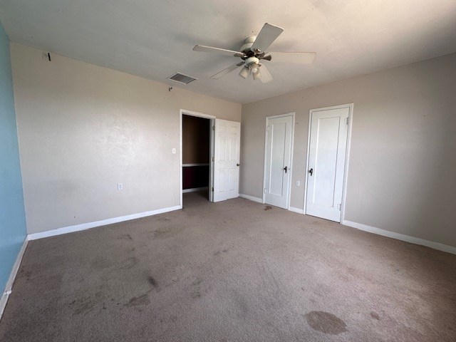 999 S County Rd 183, Snyder, TX 79549 - unfurnished bedroom featuring baseboards, carpet, two closets, and ceiling fan