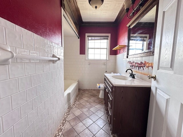 999 S County Rd 183, Snyder, TX 79549 - full bathroom featuring tile walls, tile patterned flooring, vanity, toilet, and a bath