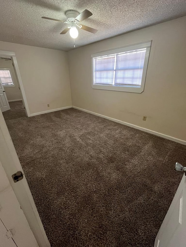 unfurnished room with carpet, baseboards, ceiling fan, and a textured ceiling