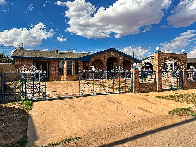 ranch-style house featuring a gate, brick siding, and fence