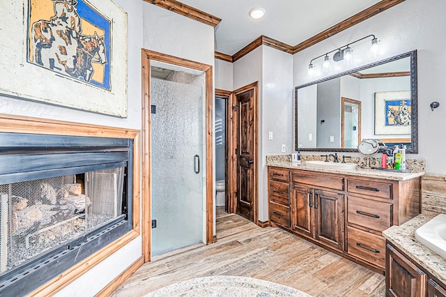 full bathroom with a multi sided fireplace, crown molding, hardwood / wood-style floors, vanity, and independent shower and bath